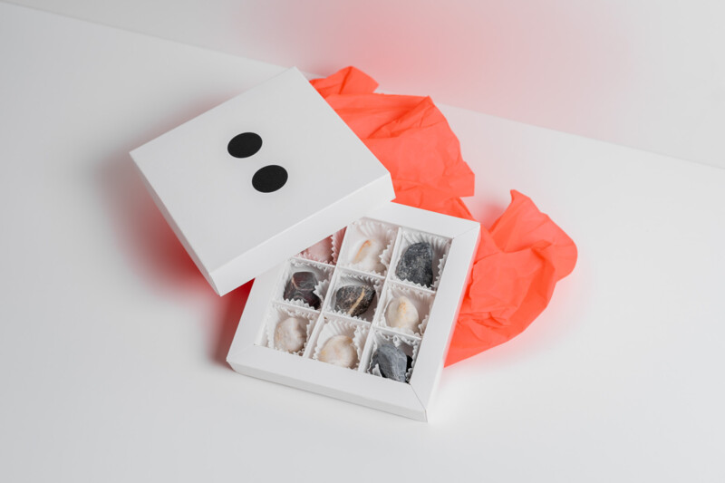 Eine kleine, wei&szlig;e Pralinenschachtel mit dem FUTUN-Logo auf dem Deckel. Der Inhalt der Schachtel ist sichtbar, darin befinden sich kleine Steine anstelle von Pralinen.